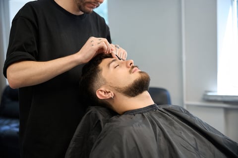 Barber applying wax between eyebrows